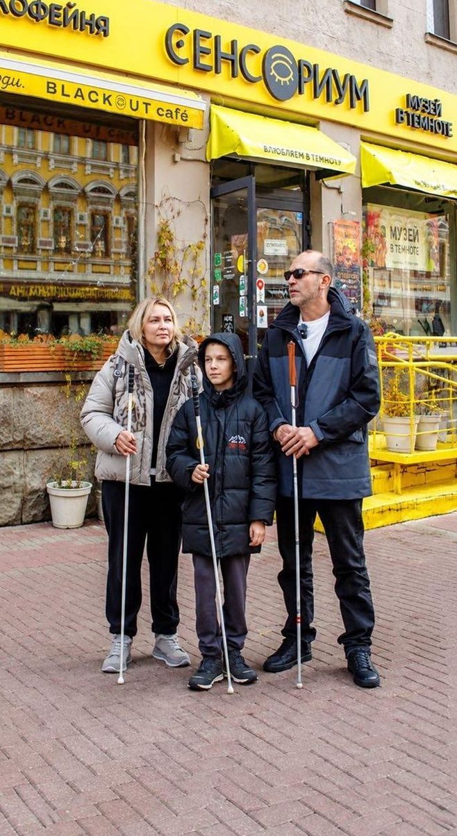 Семья с белыми тростями у входа в музей